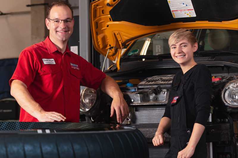 Samuel Wagner mit der Auszubildenden Sara. (Foto: Wirtschaftsförderung Region Meißen) Ein junger Mann steht lächelnd an der offenen Motorhaube eines Autos und blickt in die Kamera. Neben ihm steht eine junge Auszubildende die ebenfalls freundlich in die Kamera blickt.